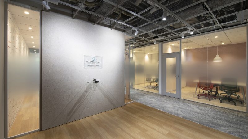 株式会社アーバンスペースのオフィスエントランス。リサイクルガラスの壁とスケルトン天井が特徴